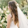 Bride with romantic half up half down hairstyle and flowing veil in outdoor setting