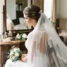 Bride with elegant updo and cathedral veil viewed from side angle in natural lighting