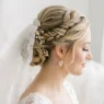 Bride with elegant twisted updo and cathedral veil shown from side angle with pearl earrings