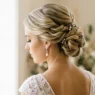 Bride with elegant twisted updo showing intricate pin placement and hair texture from three-quarter back angle