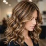 Woman with dimensional caramel highlights in brown hair showing transformation from flat to textured color