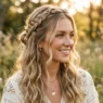 Woman with completed braided half up boho hairstyle featuring side braids and loose waves in golden lighting