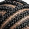 Close-up detail of multiple cornrow braids showing intricate weaving pattern in natural black hair