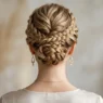 Woman with elegant braided updo showing intricate pin placement and twisted sections at nape of neck
