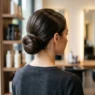 Woman with long hair styled in elegant low bun updo viewed from behind in salon setting