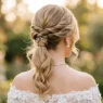 Elegant low wedding ponytail from behind showing twisted sections and romantic tendrils at nape