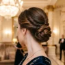 Woman with elegant mother of the bride updo in luxury hotel lobby with chandelier lighting