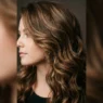 Woman with dimensional brown highlights in bouncy mid-length layered hair showing depth and movement
