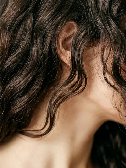 Close-up portrait of woman with expertly layered short hair showing natural texture and movement in soft studio lighting