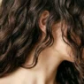 Close-up portrait of woman with expertly layered short hair showing natural texture and movement in soft studio lighting