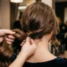 Woman's long hair being gathered at the nape by stylist's hands in preparation for updo