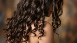 Long wavy hair cascading over woman's shoulder showing defined spiral curl patterns and natural shine