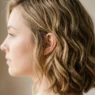 Woman with mid-length layered hair showing natural waves and face-framing cut