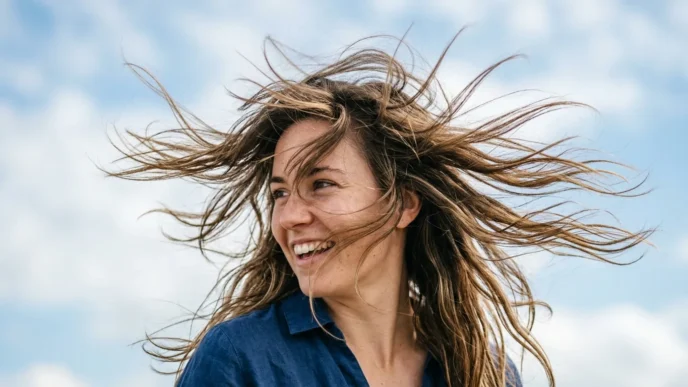 Woman with mid-length wavy hair caught in motion by gentle breeze showing natural texture and movement