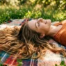 Woman with long hair spread naturally on picnic blanket in dappled sunlight showing hair texture and length
