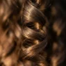 Extreme close-up of natural hair wave spiral showing light reflection and silk-like texture
