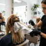 Professional colorist applying highlights with foils and precision brush in bright salon setting