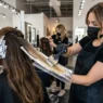 Professional colorist applying balayage with paddle brush and foil in bright salon lighting