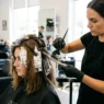 Professional stylist applying balayage highlights to client's lob-length hair with precision brush technique