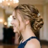 Young woman with elegant twisted prom updo showing romantic side angle and face-framing pieces
