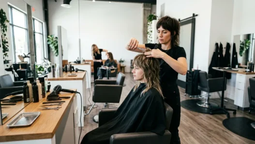 Professional stylist cutting shaggy wolf cut layers in modern salon with natural lighting