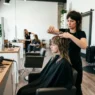 Professional stylist cutting shaggy wolf cut layers in modern salon with natural lighting