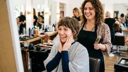 Woman with delighted expression admiring her fresh Wendy cut in salon mirror with stylist standing behind her