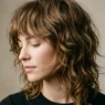 Woman with textured shag haircut and wispy bangs in editorial lighting showing layered movement
