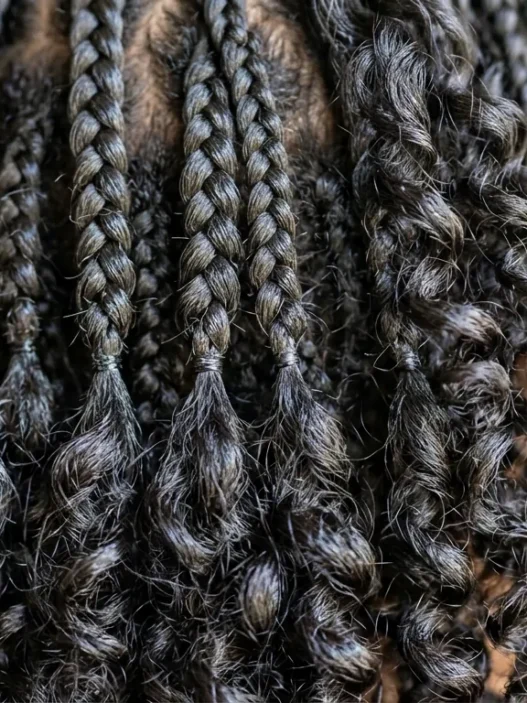 Close-up showing contrast between structured short braids and natural curl texture with dimensional movement