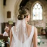 Bride with simple low chignon wedding hairstyle showing clean elegant neckline and pearl earrings