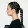 Woman showing braided ponytail from side profile with Dutch braid foundation leading to classic three-strand braid