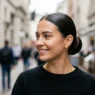 Woman with ultra-sleek low bun reflecting light like glass in natural daylight
