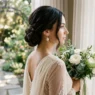 Bride with long dark hair in sophisticated low chignon showing three-quarter profile with pearl earrings