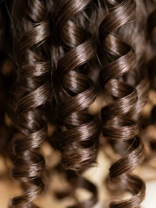 Close-up macro view of defined spiral curls showing natural hair texture and light reflection