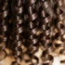Close-up macro view of defined spiral curls showing natural hair texture and light reflection