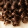 Extreme close-up of perfectly formed spiral wave pattern in brunette hair showing curl structure
