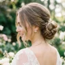 Bride with shoulder-length textured low bun showing loose face-framing pieces and pearl earrings