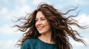 Woman with layered hair caught in motion showing natural texture and movement in bright daylight
