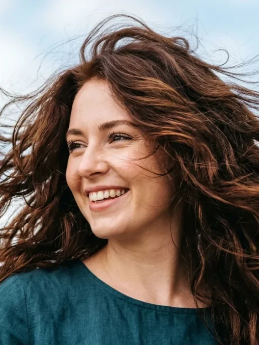 Woman with layered hair caught in motion showing natural texture and movement in bright daylight