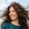 Woman with layered hair caught in motion showing natural texture and movement in bright daylight