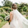 Bride with elegant updo and cathedral veil in garden setting showing hair and veil attachment