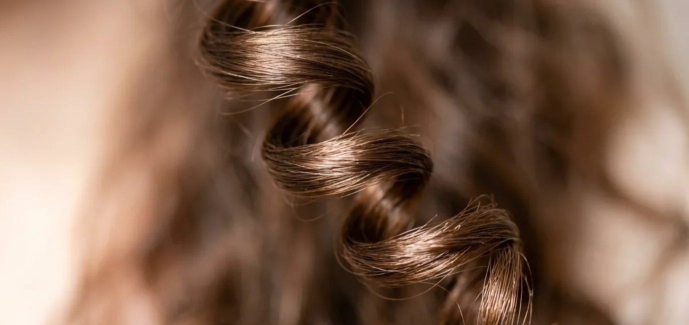 Extreme close-up of a single spiral curl showing light reflection and natural hair texture