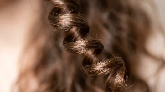 Extreme close-up of a single spiral curl showing light reflection and natural hair texture