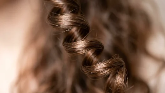 Extreme close-up of a single spiral curl showing light reflection and natural hair texture