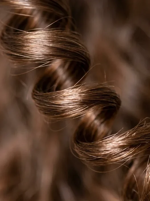 Extreme close-up of a single spiral curl showing light reflection and natural hair texture