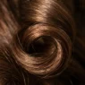 Extreme close-up of single spiral curl showing light reflecting off hair cuticle with shallow depth of field