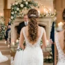 Bride with elegant wedding ponytail showing volume at crown and textured curls from behind at ceremony
