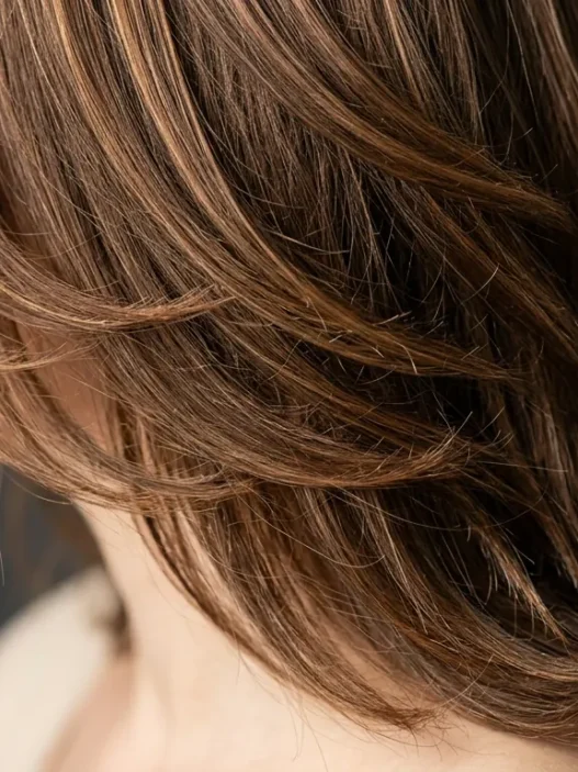 Woman with perfectly layered shoulder-length hair showing subtle highlights from jawline to crown