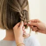 Close-up of hands braiding chin-length bob hair with three strands being woven together