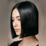 Woman with sleek chin-length bob showing glossy finish in soft studio lighting